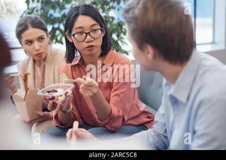 Groupe de jeunes gens d'affaires qui mangent de la nourriture à emporter et discuter pendant la pause déjeuner au bureau, espace de copie Banque D'Images
