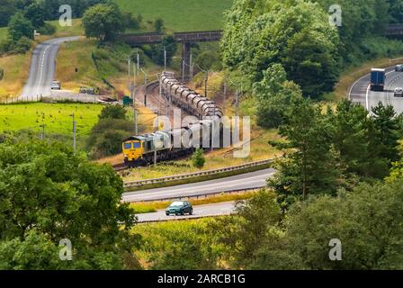 La principale laine de la côte ouest à Beck Foot Cumbria. Une locomotive de classe 66 transportant des wagons à charbon vers le nord. La Old Scotch Road est vue sur la gauche avec TH Banque D'Images