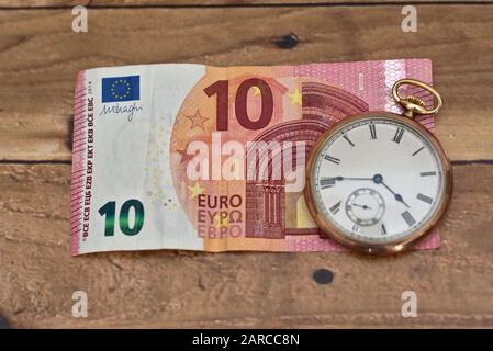 Prise de vue en grand angle d'une horloge sur un euro de dix sur une table en bois - temps et concept d'affaires Banque D'Images