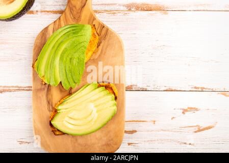 Toasts de patate douce avec avocat sur planche en bois. Concept de repas sain. Cuisine propre, cuisine végétarienne, vue sur le dessus Banque D'Images