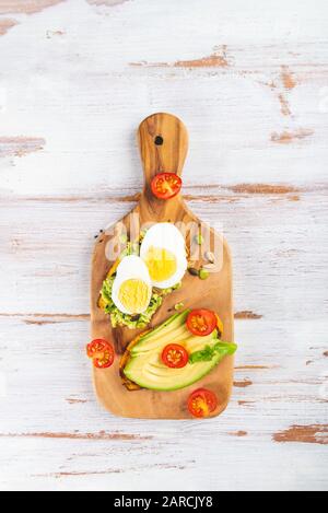 Toasts de pommes de terre douces avec avocat, œufs durs, tomates et graines de sésame sur carton en bois. Concept de repas sain. Cuisine propre, cuisine végétarienne, vue sur le dessus Banque D'Images