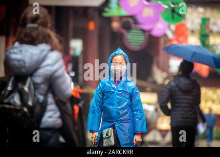 Shanghai, Chine, 25 janvier 2020, une femme portant un masque marche dans la rue en imperméable Banque D'Images