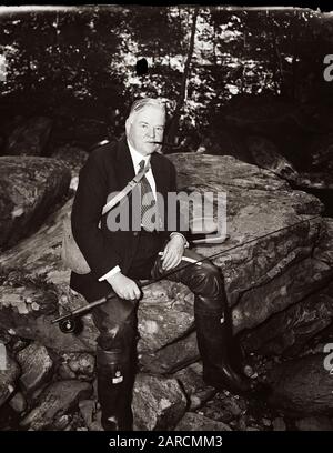 Le président américain Herbert Hoover - portant une cravate de costume et une fédora - pêche à la mouche dans un petit ruisseau en 1936. Banque D'Images