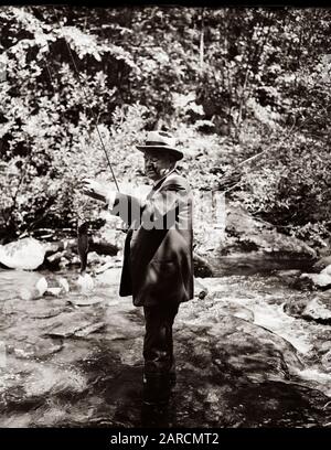 Le président américain Herbert Hoover - portant une cravate de costume et une fédora - pêche à la mouche dans un petit ruisseau en 1936. Banque D'Images