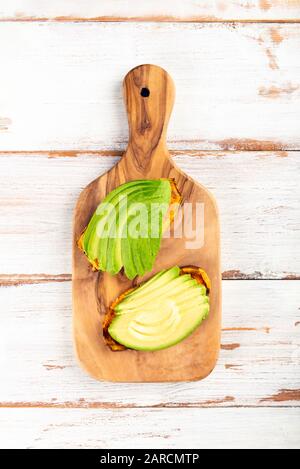 Toasts de pommes de terre douces avec avocat, œufs durs, tomates et graines de sésame sur carton en bois. Concept de repas sain. Cuisine propre, cuisine végétarienne, vue sur le dessus Banque D'Images