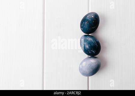 Beau groupe ombre bleu oeufs de Pâques avec des œufs de caille et des plumes sur un fond en bois blanc. Concept de Pâques. Œufs de bordure. Espace de copie pour le texte. Couleur bleu classique de l'année 2020 Banque D'Images