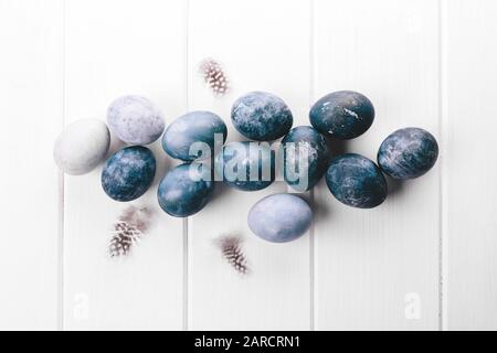 Beau groupe ombre bleu oeufs de Pâques avec des œufs de caille et des plumes sur un fond en bois blanc. Concept de Pâques. Œufs de bordure. Espace de copie pour le texte. Couleur bleu classique de l'année 2020 Banque D'Images