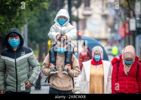 Shanghai, Chine, 25 janvier 2020, un groupe de personnes portant des masques marche en bas de la rue le jour de pluie, Edwin Remsberg Banque D'Images