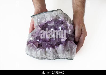 Une personne tenant un échantillon d'améthyste, montrant la cavité cristalline exposée dans une section de roche. Banque D'Images