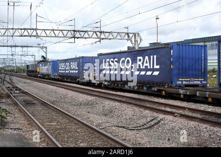 Un train de conteneurs de fret publiant les avantages environnementaux du transport ferroviaire sur route - "MOINS de CO 2...". Banque D'Images