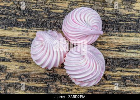 Gâteau meringue à tourbillon blanc, fouetté, gris et rose nommé Pavlova dans le processus de préparation. Tourbillons de beze blancs, gris et roses sur table en bois. Banque D'Images