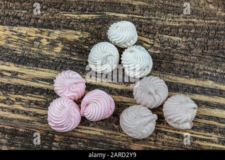 Gâteau meringue à tourbillon blanc, fouetté, gris et rose nommé Pavlova dans le processus de préparation. Tourbillons de beze blancs, gris et roses sur table en bois. Banque D'Images