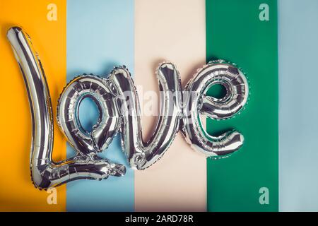 Mot d'amour d'un ballon en feuille d'argent sur fond multicolore muet. Bonne Saint Valentin concept de festival. Les ballons rendent les gens heureux. Toning vintage Banque D'Images