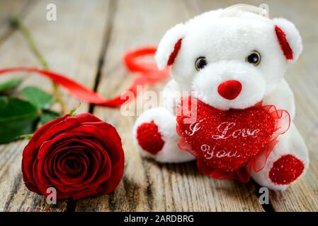 Concept de Saint Valentin. Ours en peluche blanc et rose rouge sur table en bois. Mise au point sélective. Banque D'Images