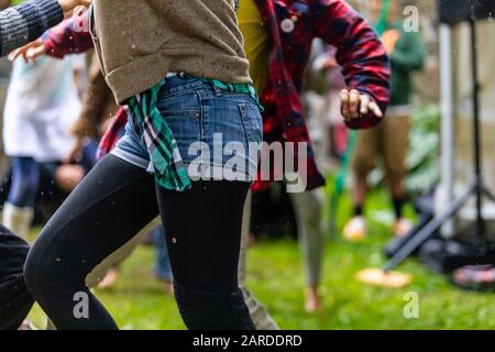 Gros plan d'une femme tendance et insouciante portant un pantalon chaud en denim lors de la course et de la danse avec un ami sur la pelouse dans le parc pendant la saison des pluies Banque D'Images