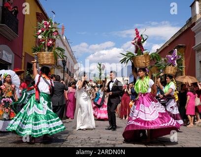 Mariée et marié encadrés par une femme dans la tenue traditionnelle partie de la parade de mariage traditionnelle (Calenda de Bodas) dans les rues d'Oaxaca. Banque D'Images