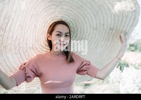 Belle femme d'Asie qu'elle aime avec le grand chapeau dans la fleur de jardin Banque D'Images