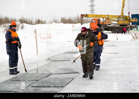 Les employés radeau des blocs de glace le long d'une chaîne coupée un lac gelé Banque D'Images