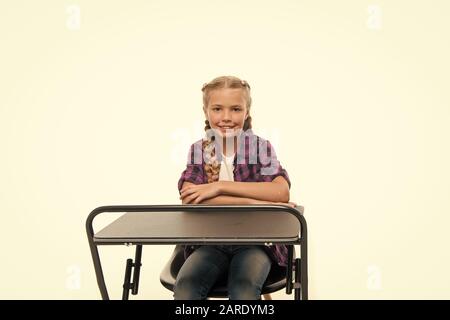 Retour à l'école. L'école mignon enfant assis au bureau isolé sur blanc. Lycéenne ayant peu de leçon à l'école primaire. Adorable petite fille en compagnie de ses heures d'école. Banque D'Images