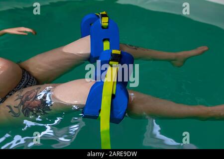 Gros plan de la partie basse des jambes d'une femme enceinte avec jambe bleue flotter près des genoux se détendre dans la petite piscine. Traitement d'aqua Banque D'Images