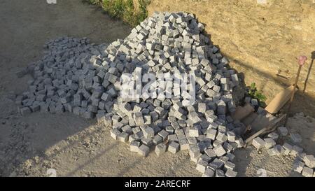 Pile de petites pierres de revêtement en granit coudées prêtes à poser sur le chemin du village Banque D'Images