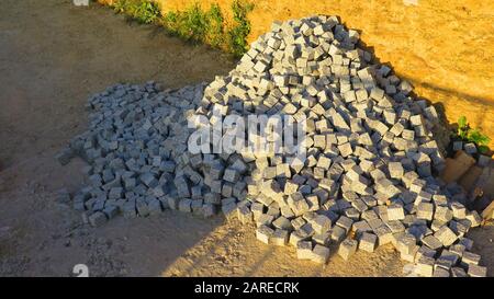 Pile de petites pierres de revêtement en granit coudées prêtes à poser sur le chemin du village Banque D'Images