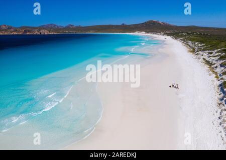 Lucky Bay, Esperance, Australie occidentale - 10 janvier 2020: Antenne de voyageurs garés van sur une plage de sable blanc avec de l'eau bleu limpide Banque D'Images