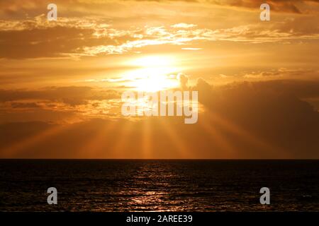 Lever du soleil et nature : un horizon doré à l'aube où les rayons de soleil traversent les nuages pour faire un beau lever du soleil. Banque D'Images