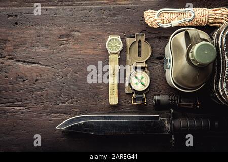 Équipement tactique militaire pour le départ. Assortiment d'équipements de randonnée de survie sur fond en bois. Vue de dessus - effet filtre à grain à film vintage St Banque D'Images