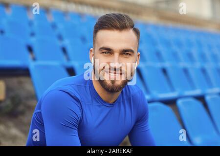 Un gars en sportswear est assis dans le stade après la formation. Banque D'Images