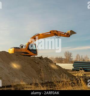 Pelle hydraulique jaune sur le chantier de terrassement d'excavation sur le chantier de construction. Processus de pose des réseaux principaux d'eaux domestiques, industrielles et pluviales. Banque D'Images