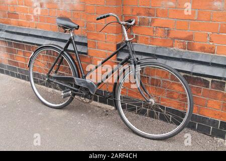 Un Vélo Vintage Ladies Penchant Contre Un Mur De Briques. Banque D'Images