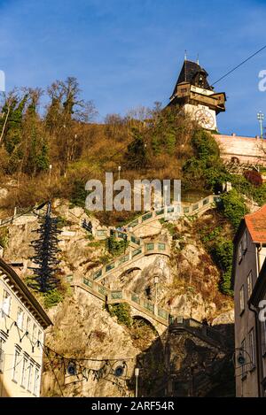 Graz, Styrie - Autriche - 24.12.2019: Ville de Graz rue et escalier à la tour de l'horloge vue Uhrturm, horloge Schlossberg en arrière-plan à la colline, touristes Banque D'Images