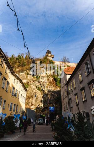 Graz, Styrie - Autriche - 24.12.2019: Ville de Graz rue et escalier à la tour de l'horloge vue Uhrturm, horloge Schlossberg en arrière-plan à la colline, touristes Banque D'Images