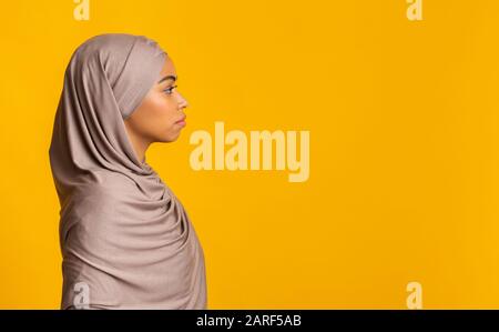 Portrait de profil d'une femme musulmane noire en hijab sur fond jaune Banque D'Images