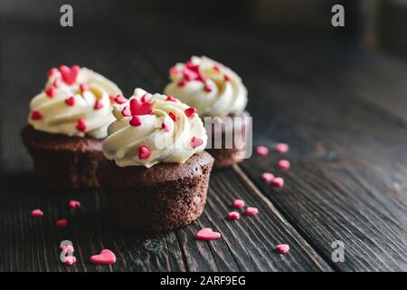 Valentin cupcakes, décoré avec des coeurs doux sur la table en bois sombre. Place pour le texte. Banque D'Images