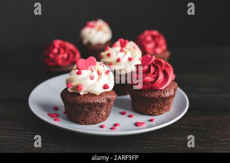 Des cupcakes de Saint-Valentin, servis sur la plaque et décorés de coeurs doux. Table en bois sombre. Mise au point sélective. Banque D'Images