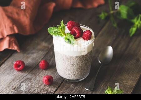 Boudin de Chia dans un pot en verre avec framboises et yaourt grec sur une table en bois. Repas végétarien ou en-cas sains pour le petit déjeuner Banque D'Images