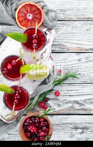 Liqueur alcoolique à partir d'une canneberge dans un verre. Canneberge, citron vert, romarin. Sur un fond rustique. Vue de dessus. Espace libre pour votre texte. Banque D'Images