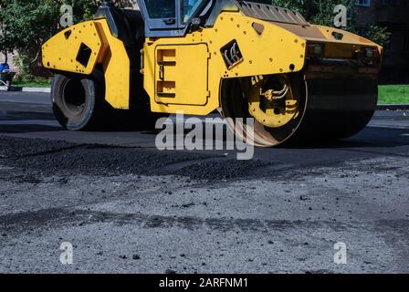 Rouleur dans la zone résidentielle, travaux de rénovation de routes asphaltées en été Banque D'Images