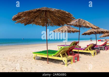 Chaises longues avec parasols sur une plage tropicale ensoleillée à GOA, Inde Banque D'Images