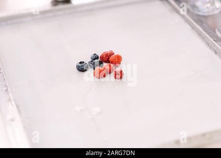 Baies sur une fine feuille de crème glacée blanche. Bleuets et framboises frais sur une feuille blanche. Délicieux dessert. Banque D'Images