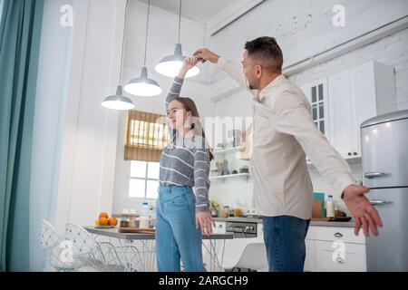 Fille adolescent dansant avec papa dans la cuisine. Banque D'Images