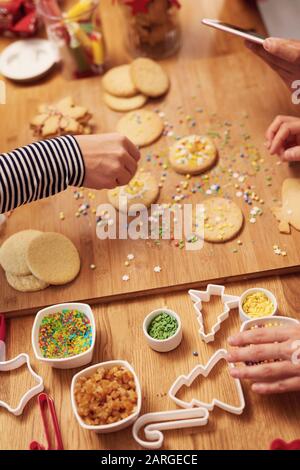 Gros plan sur les mains de la femme décorant les cookies pour Noël Banque D'Images