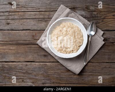 Grand bol de flocons d'avoine savoureux et sains pour le petit déjeuner, repas du matin. Vue sur le dessus, vue rapprochée, table rustique en bois Banque D'Images