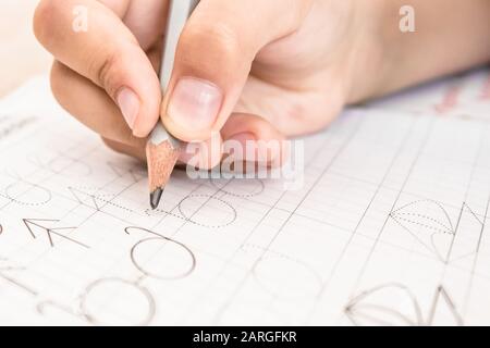 Un écolier qui écrit de près. Crayon dans la main des enfants. Le garçon écrit. Banque D'Images