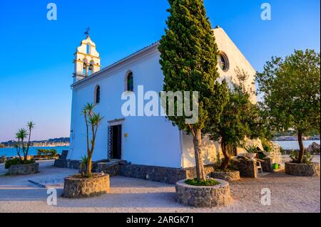 Église Ypapanti - Beau paysage au coucher du soleil dans la baie de Gouvia - petite ancienne église blanche sur un quai, île de Corfou, mer Ionienne, Grèce, Europe Banque D'Images