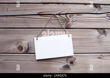 Toile de fond en bois naturel, plaque signalétique blanche suspendue sur corde. Maquette, horizontale. Banque D'Images