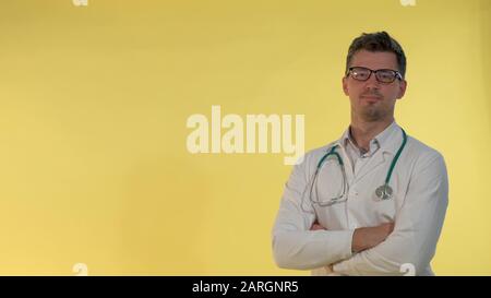 Un jeune médecin gai dans un manteau de laboratoire hochant la tête montrant qu'il est d'accord avec quelque chose. Il dans des lunettes et avec stéthoscope sur les épaules. Banque D'Images