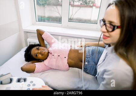 Jeune médecin de femme professionnelle faisant une échographie des reins de la jeune femme africaine patient dans la clinique médicale moderne Banque D'Images